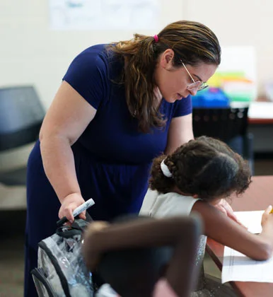 A teacher assists a young student