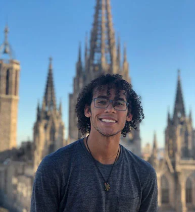 An Arcadia student smiling with a European cathedral behind him.