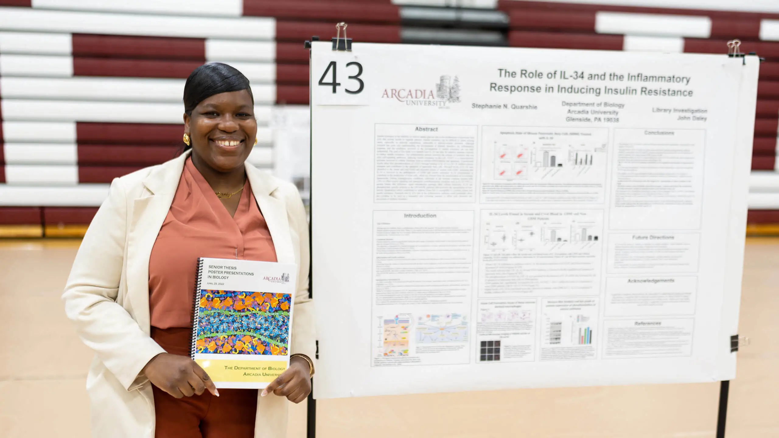 Stephanie Quarshie smiling while standing in front of her capstone project.