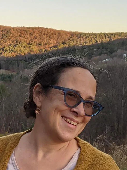 A portrait of Dr. Ellen Skilton, professor of Education in front of autumn-leafed mountains