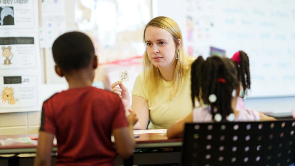 A teacher works with young students.