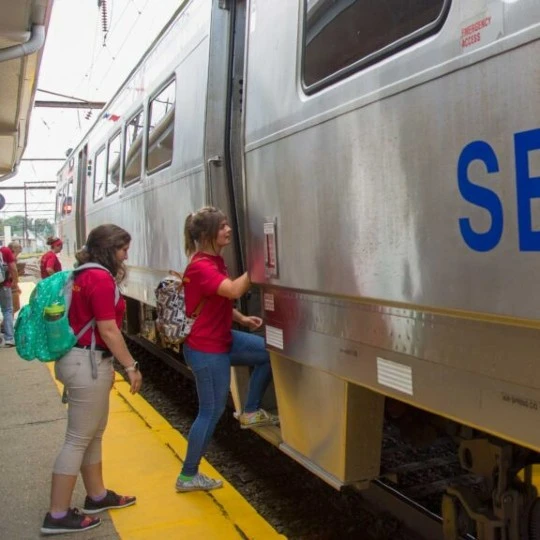 Two students climb aboard the local train.