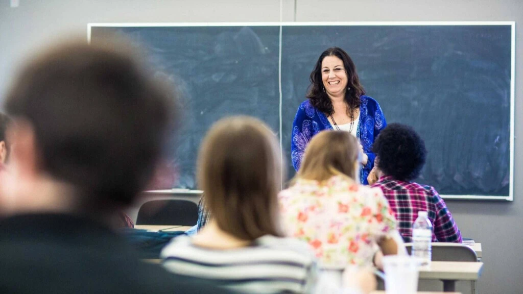 Jojo Lucena smiles while instructing a classroom full of students