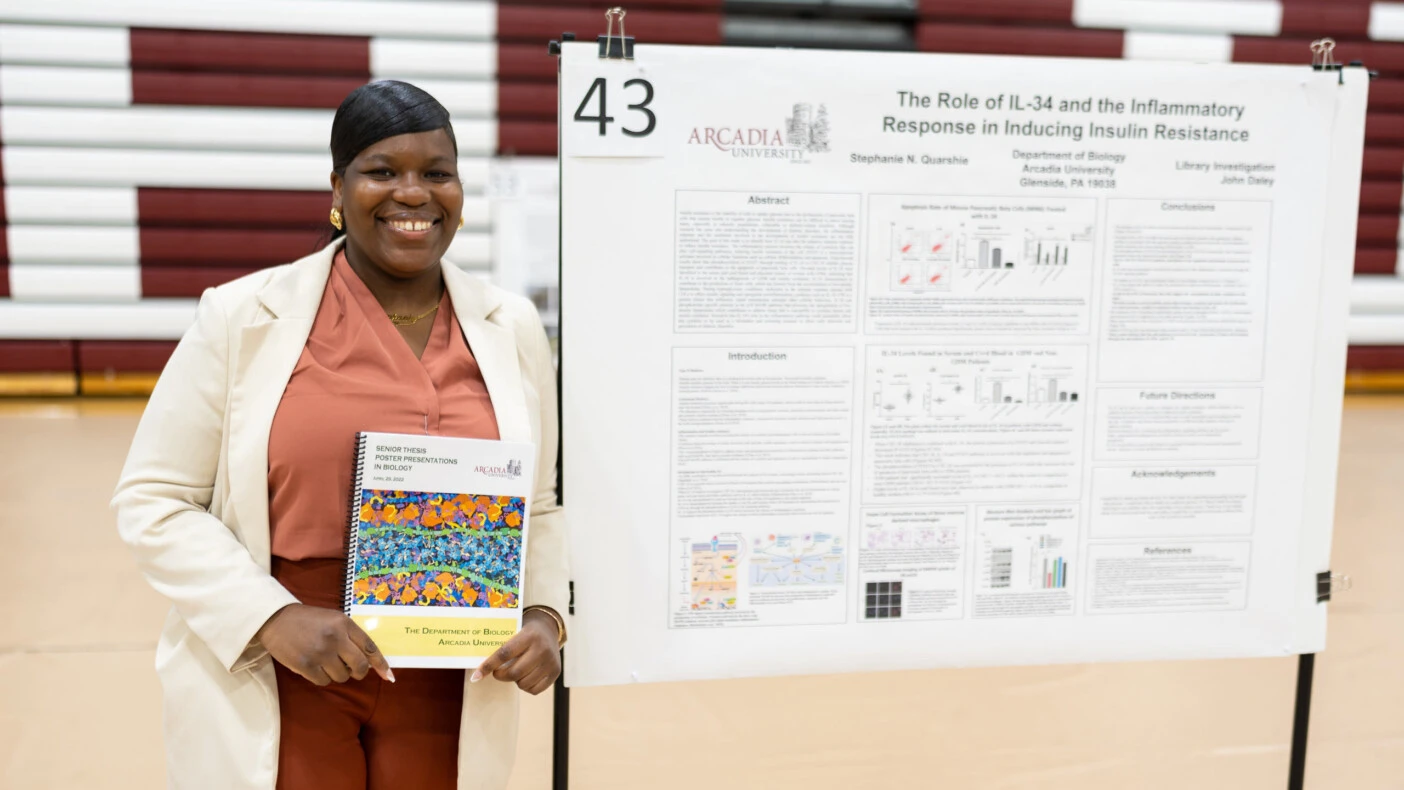 Stephanie Quarshie smiling while standing in front of her capstone project.
