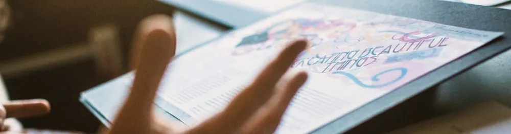 Hands in front of a piece of paper. The paper contains calligraphic text and plain text.