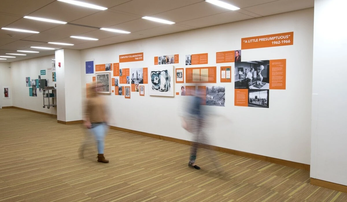 People walking through a gallery, passing an informative art installation