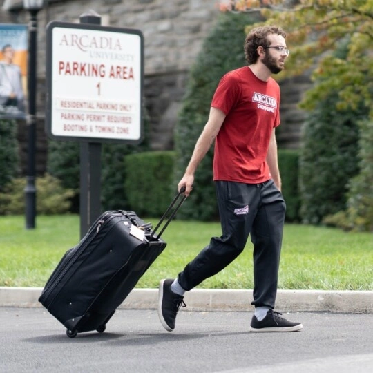A student in "Parking Area 1" pulling his luggage