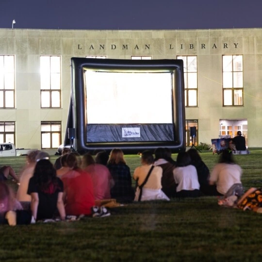 A group sitting on Haber Green watching a movie