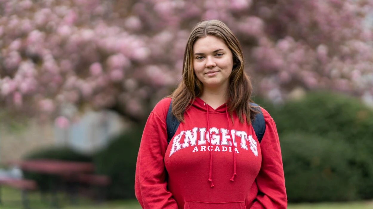 A woman student wearing a "KNIGHTS ARCADIA" hoodie