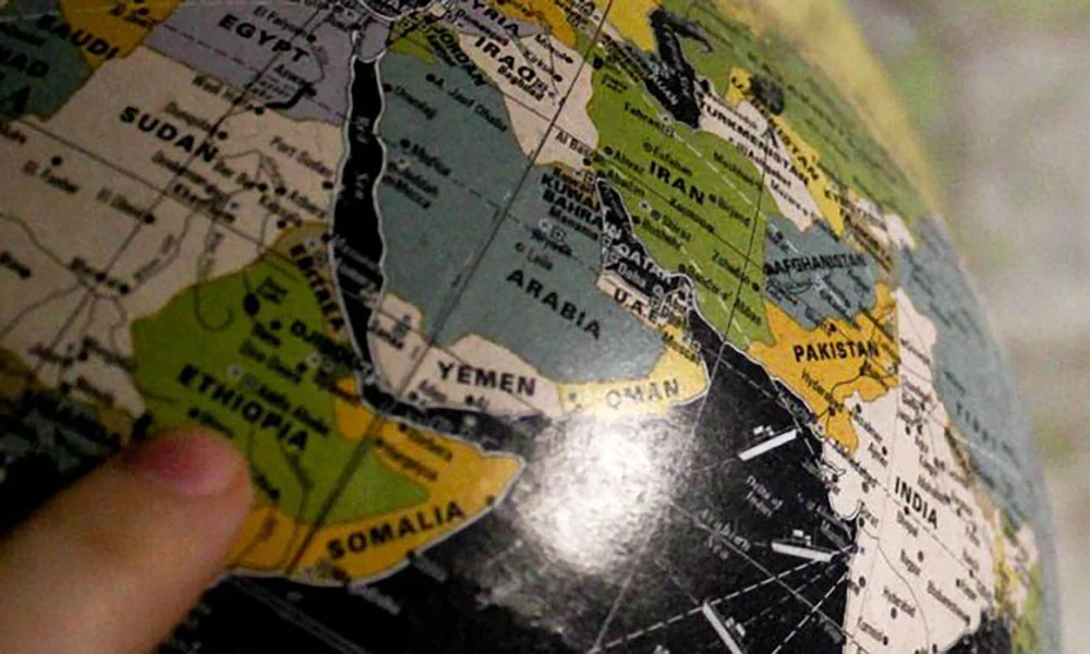 A mapped globe with a hand points to Ethiopia.