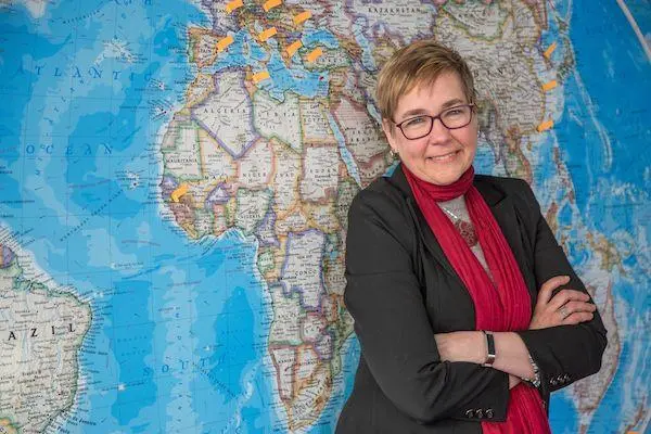 Dr. Sandra Crenshaw stands in front of a world map