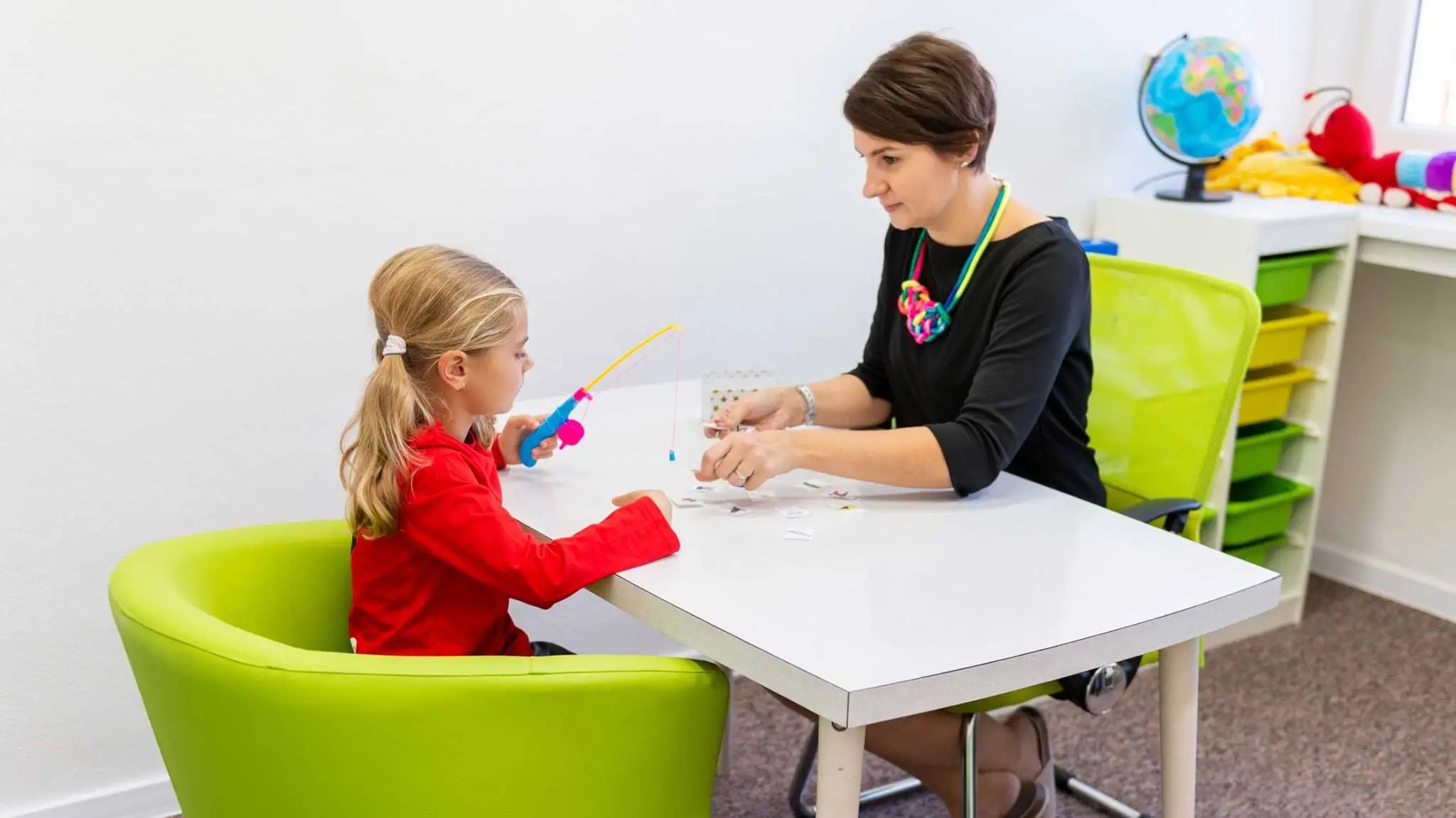 Child and woman performing learning exercise at table.