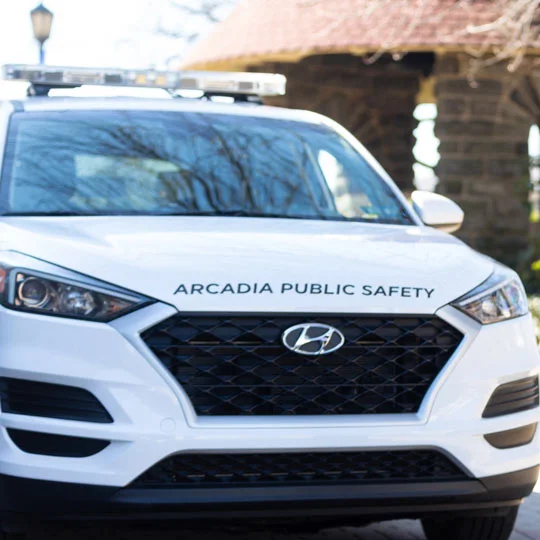 An Arcadia Public Safety patrol car faces the camera parked just outside of a campus building