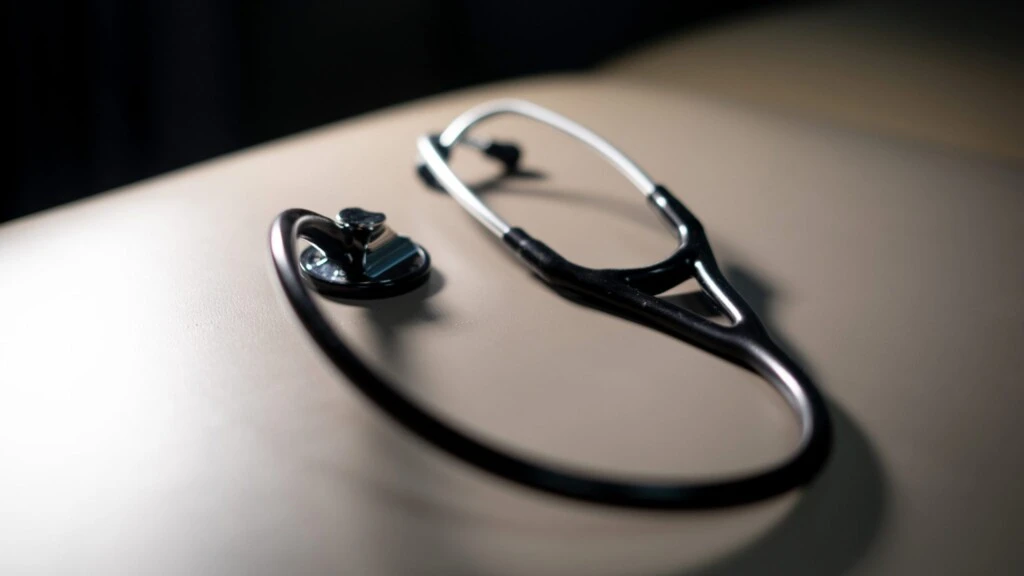 A stethoscope rests on an exam table.