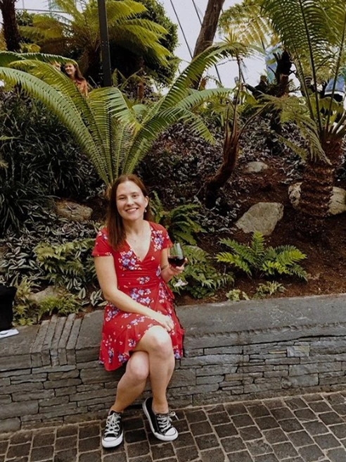 Allie Nye, Global Media Major, sits in front of a tropical garden overseas and has coffee.