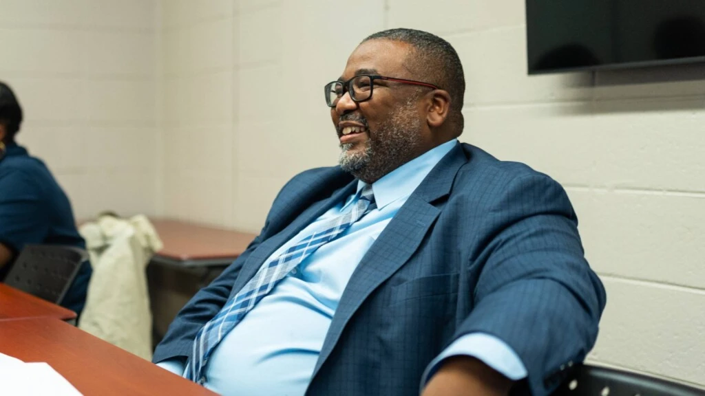 A student in a suit and tie listens to a doctorate level education class.