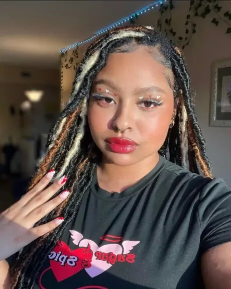 Student taking a selfie with red and white makeup and nails on