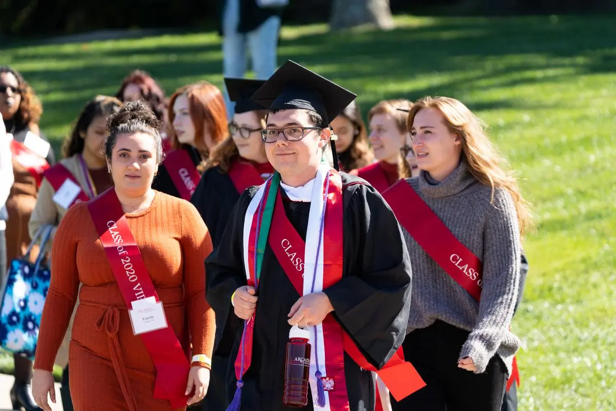 An alumni from the class of 2020, wearing their cap and gown, are celebrated in a ceremony during the 2022 Homecoming & Family Weekend