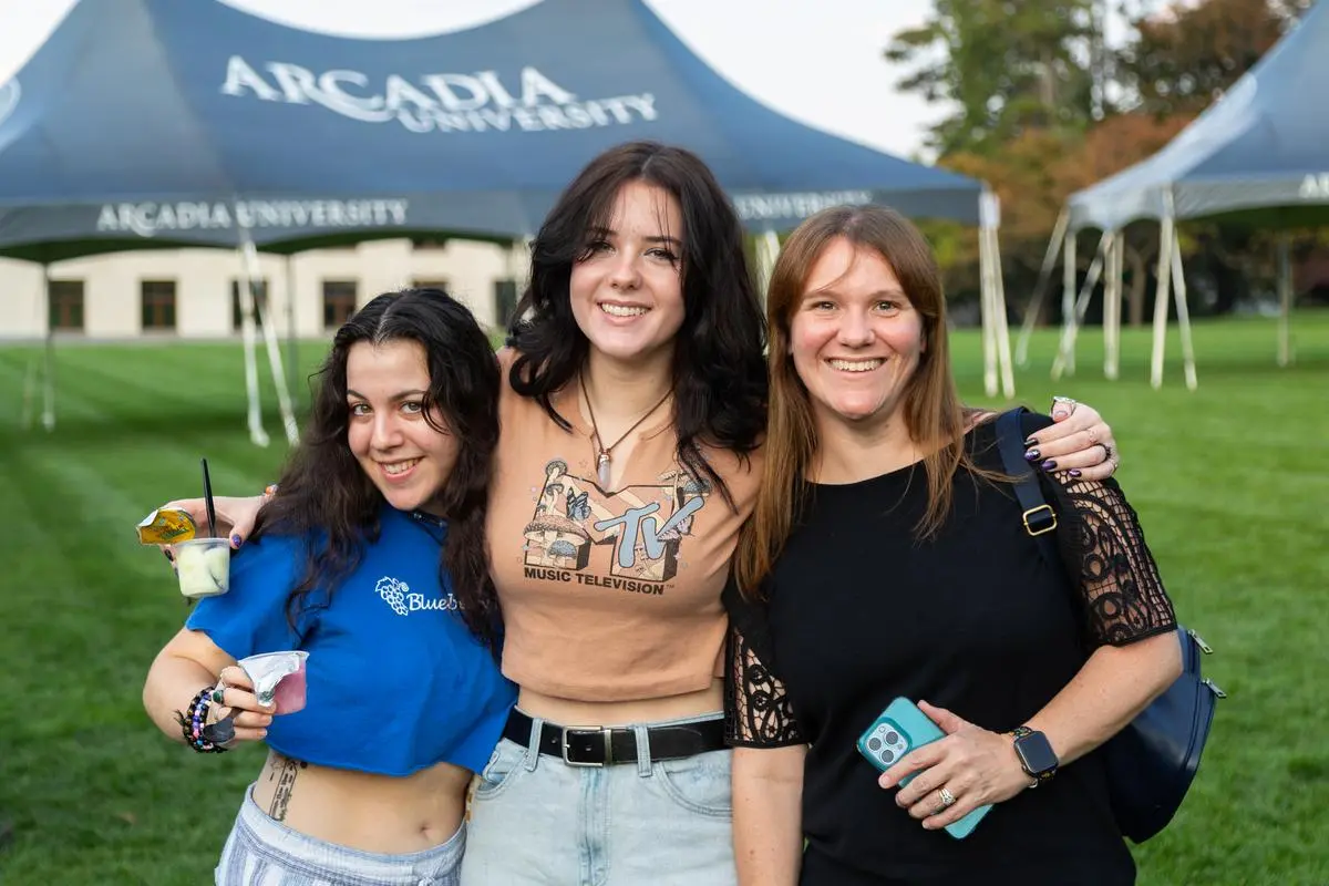 Three students pose for a photo with their arms around each other during Homecoming & Family Weekend