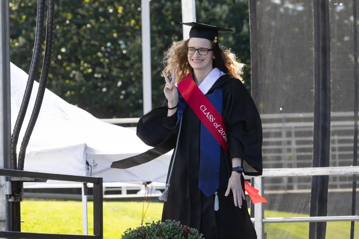 An alumni from the class of 2020, wearing the cap and gown, is celebrated in a ceremony during the 2022 Homecoming & Family Weekend
