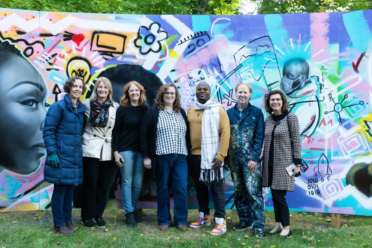 Members of the university community pose with Amir Campbell after he finishes his mural