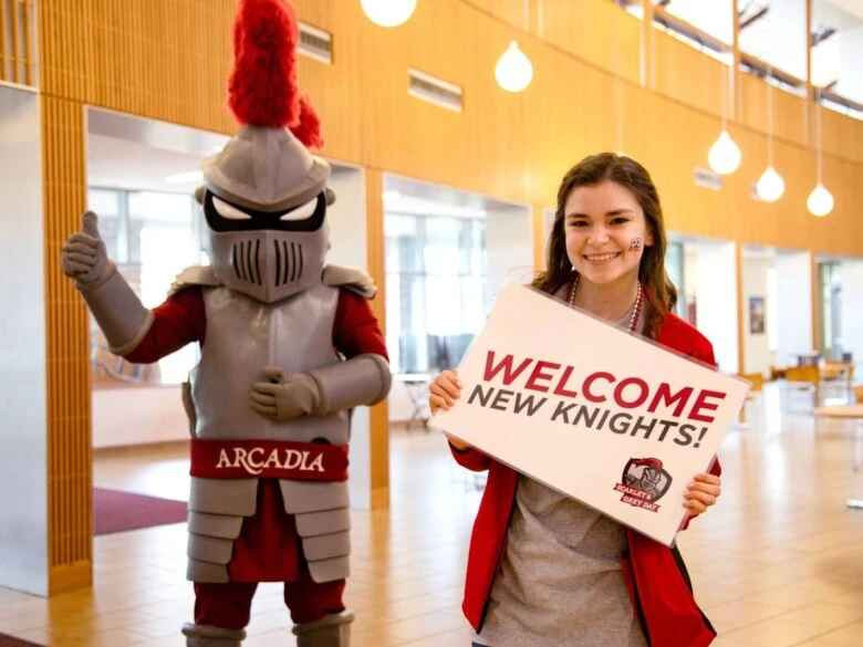 Arcadia Knight mascot and smiling student great new students with Welcome New Knights sign.