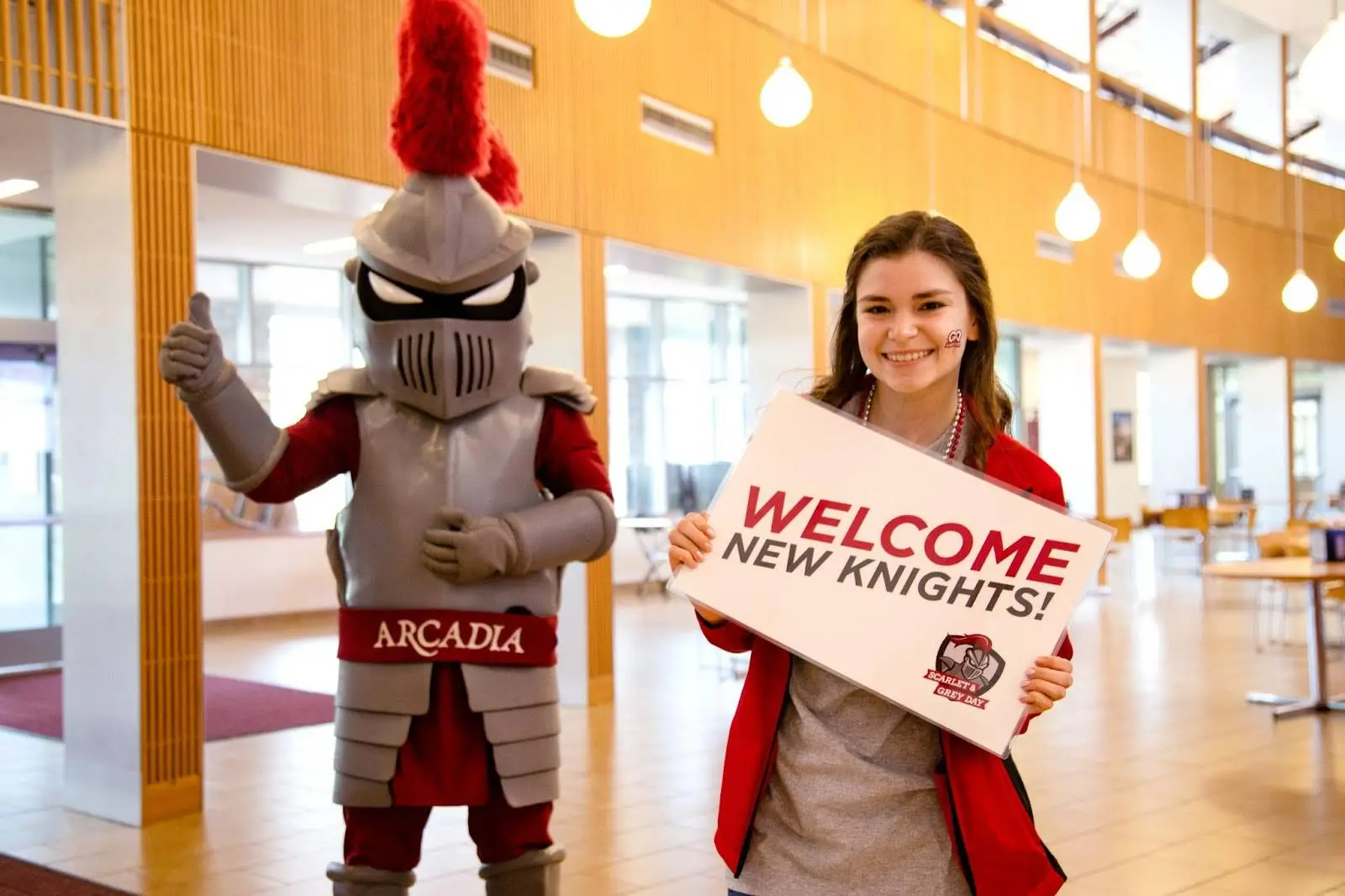Arcadia Knight mascot and smiling student great new students with Welcome New Knights sign.