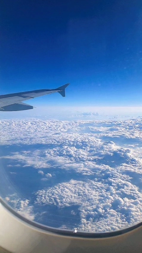 a photo from a plane window showing clouds and the wing of a plane
