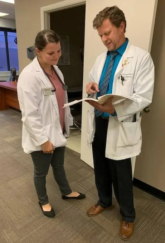 A physician instructor and student review a chart in a medical facility.