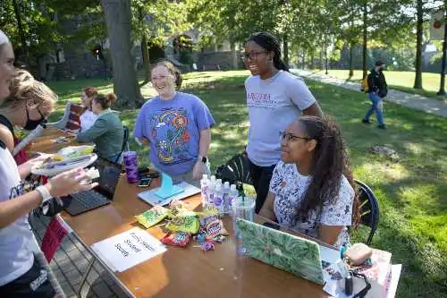 Students laughing around a table outdoors at the Activities Fair