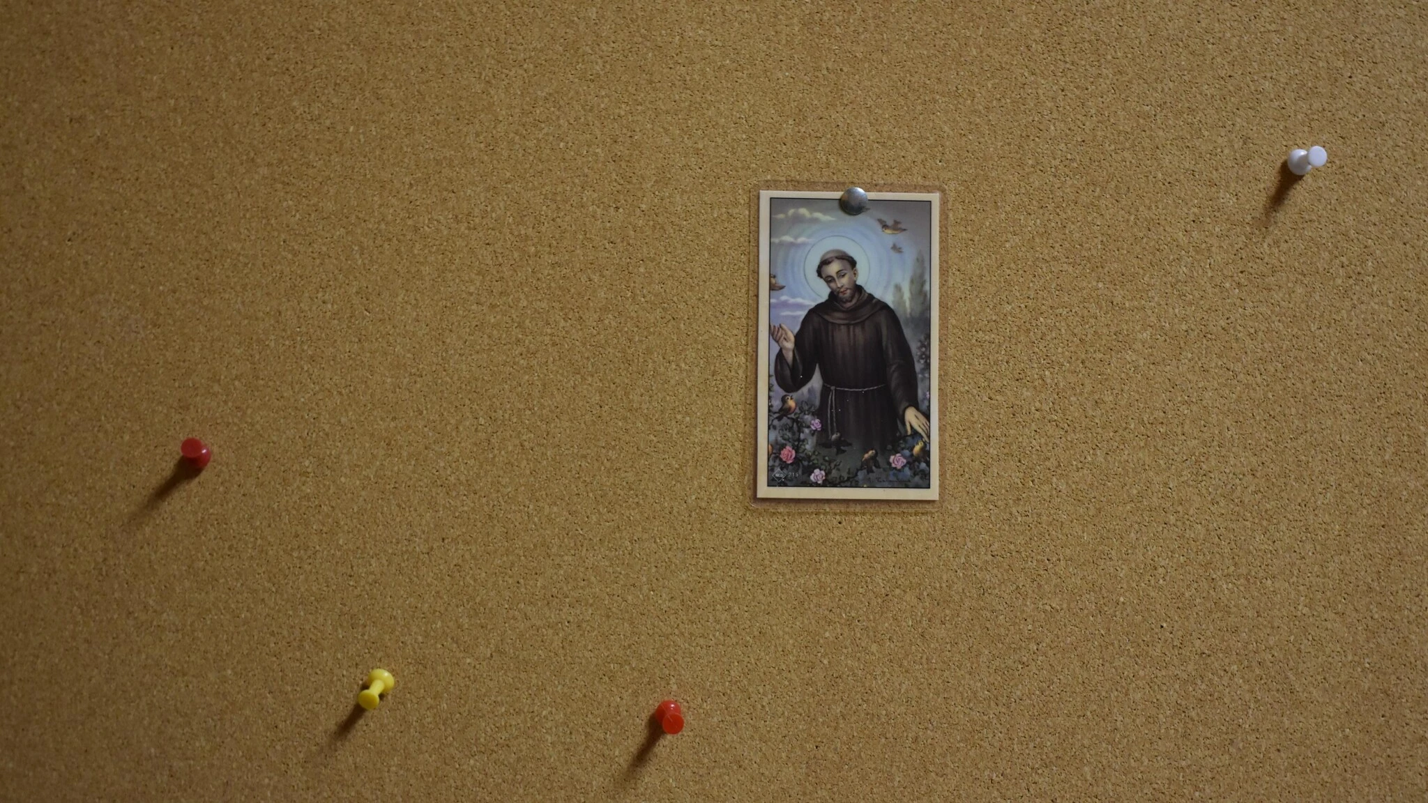 a prayer card pinned on an otherwise empty bulletin board