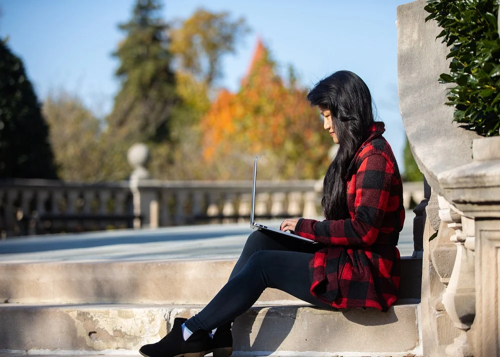 A graduate student enjoys time outside on campus in the fall.