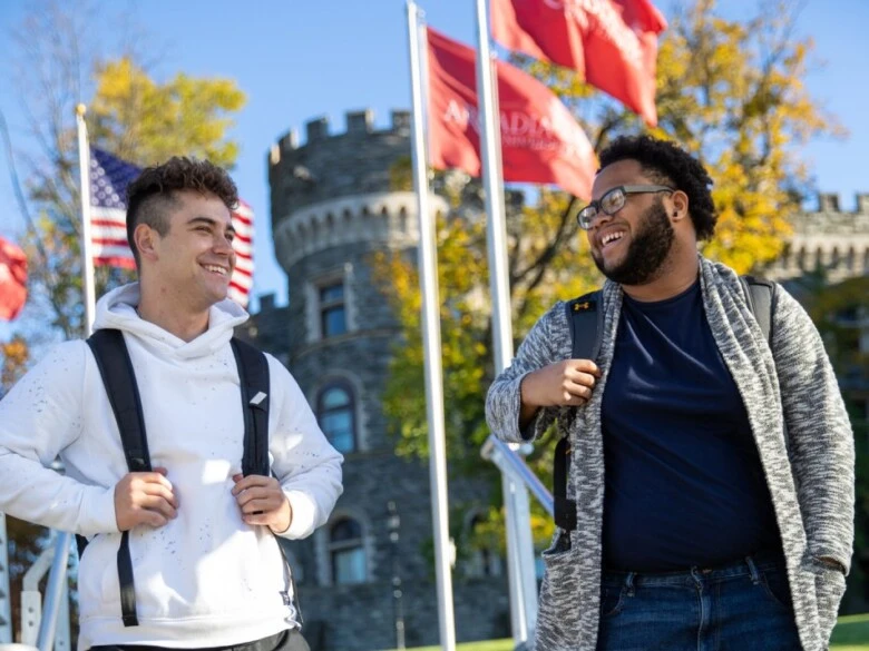 graduate students walk by Grey Towers and Arcadia red flags