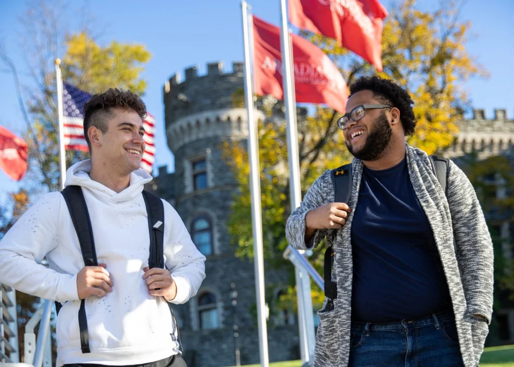 graduate students walk by Grey Towers and Arcadia red flags
