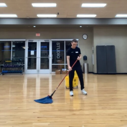 Patrick Ensmenger '23 mopping a wood floor