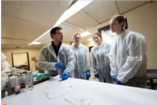 Dr. Oldoni, left, teaching students in the lab.