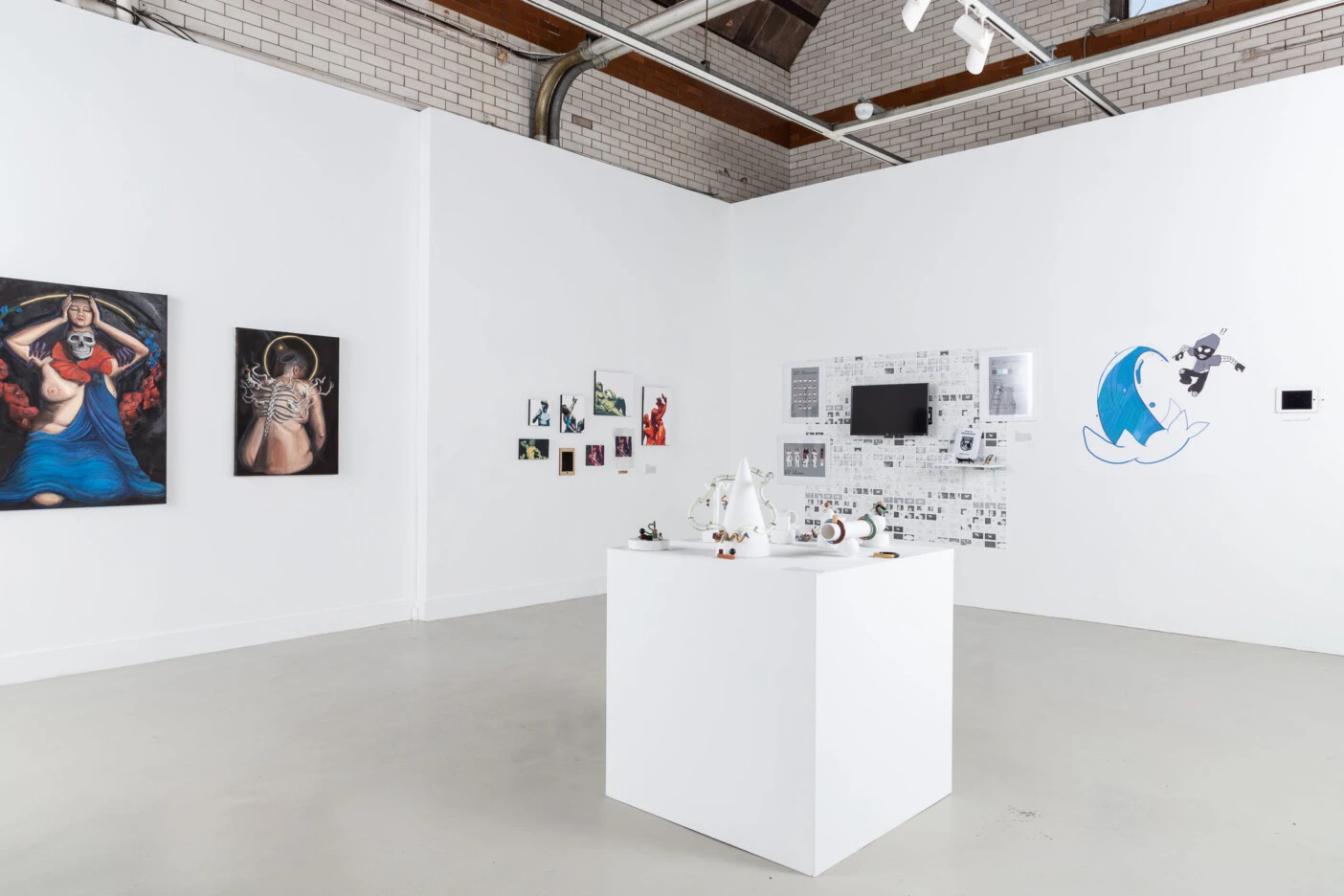A white room gallery showing different artworks and a block exhibition in the center