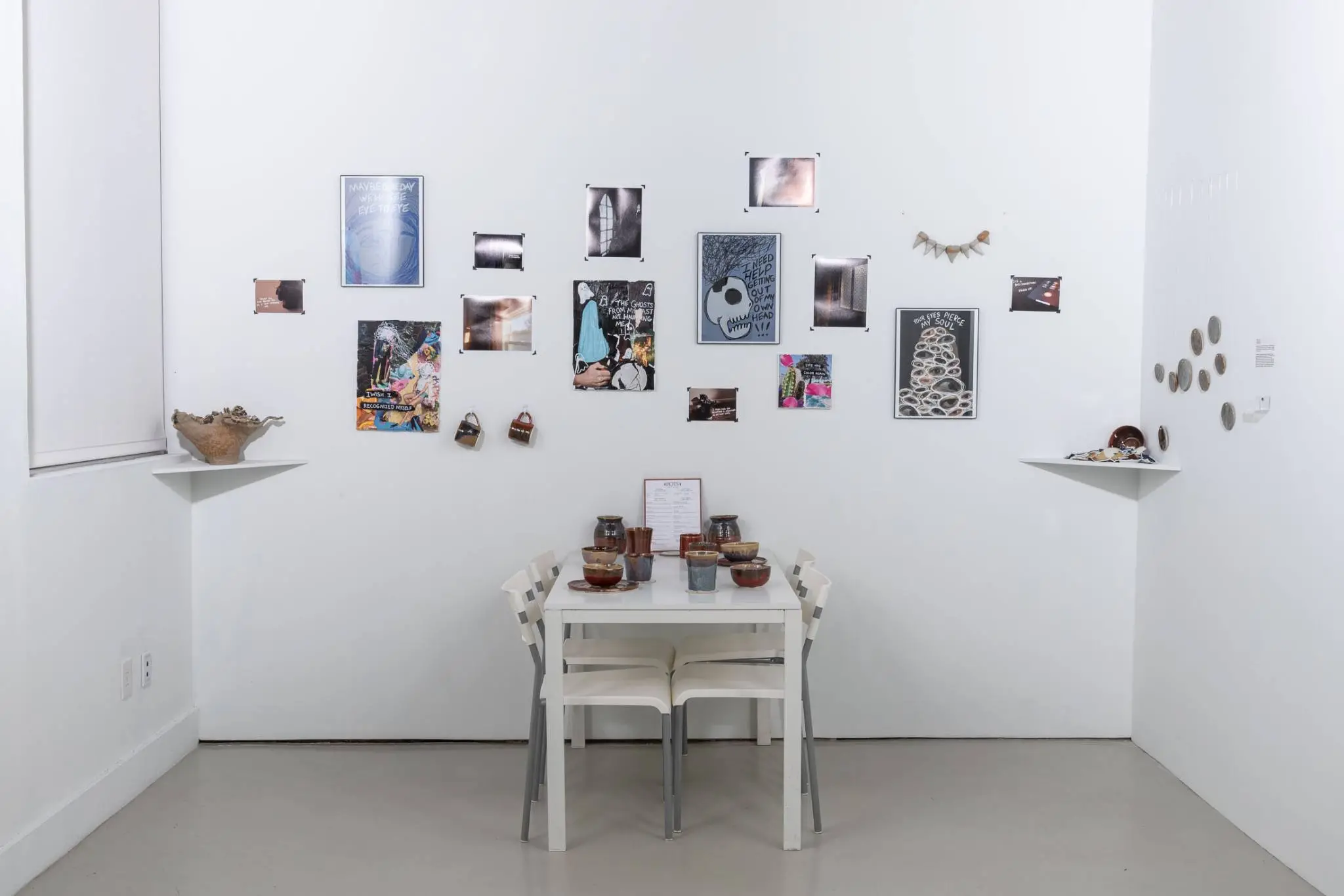 Several pieces of artwork on display on a white wall and table