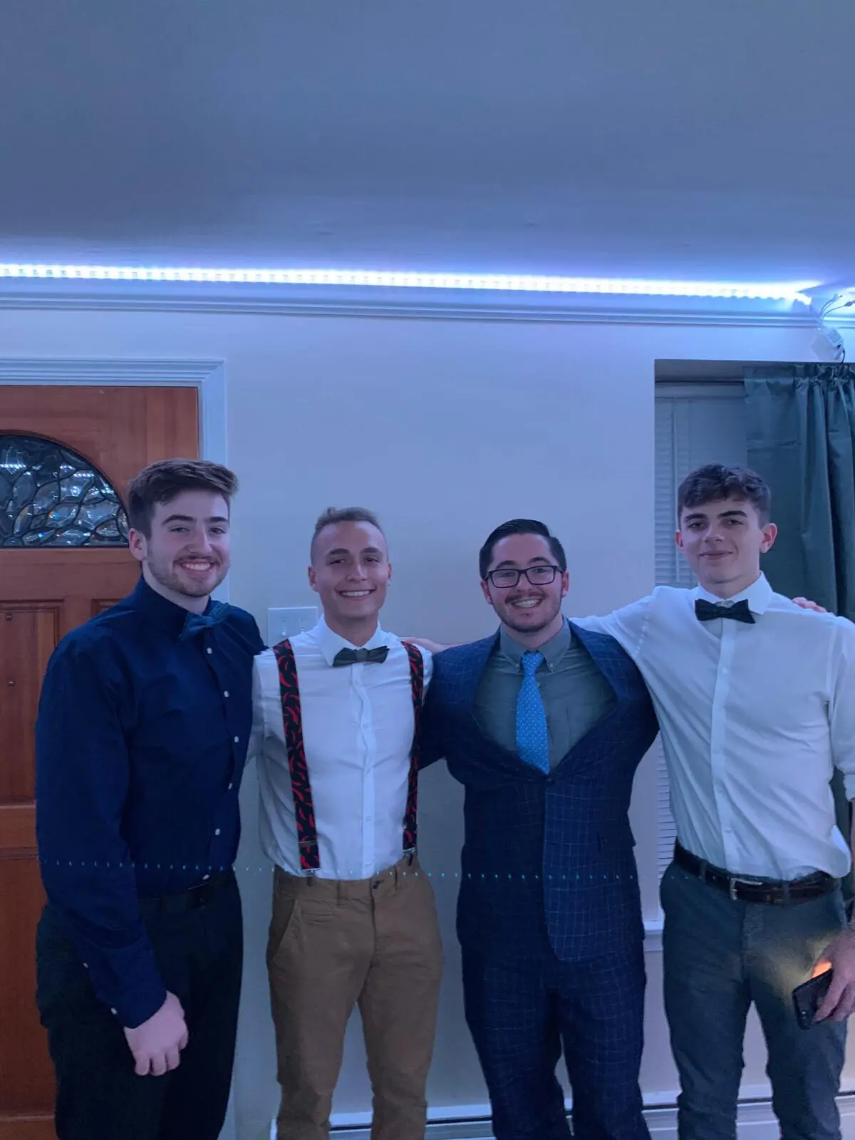 Patrick Ensmenger '23 in dress clothes with his arms around three friends, also dressed up