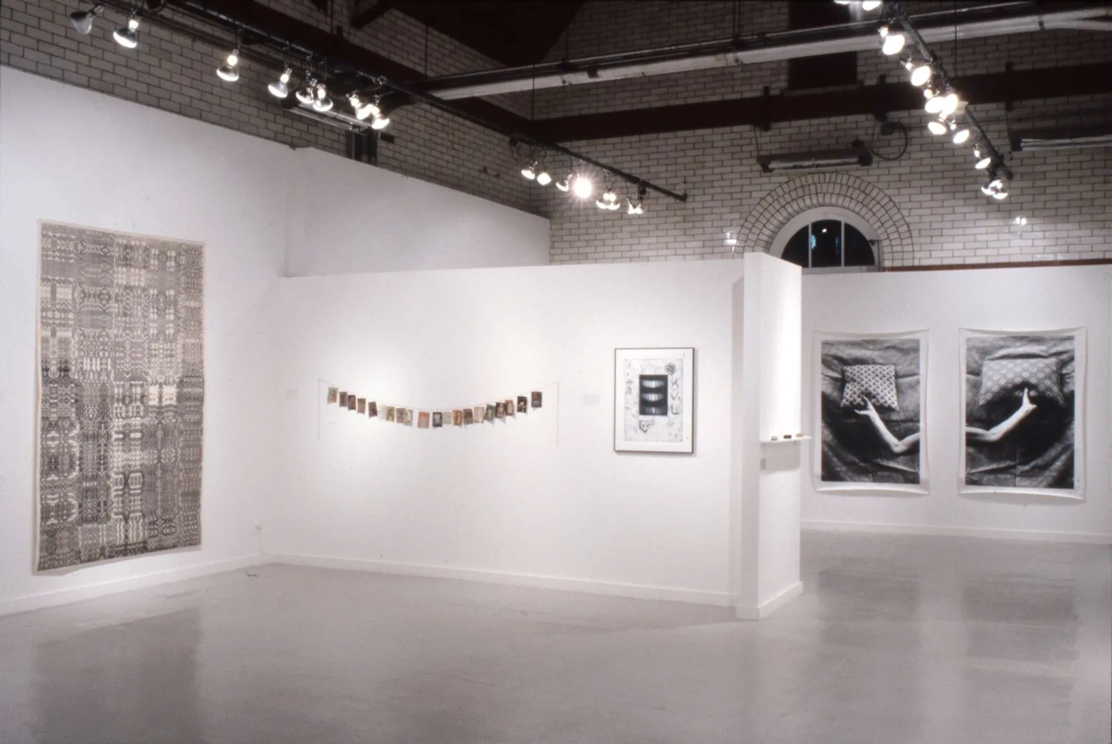 A white gallery space exhibiting several artwork pieces