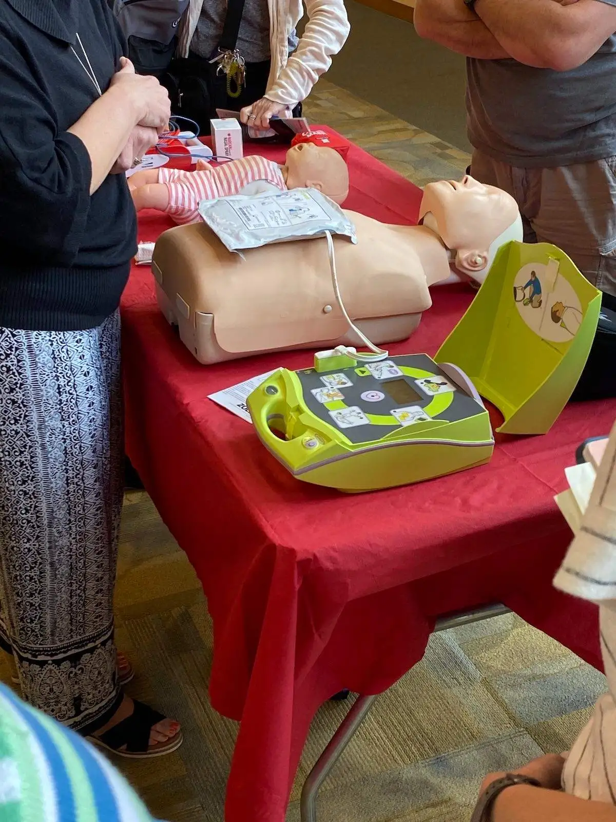 An AED sits open next to a dummy