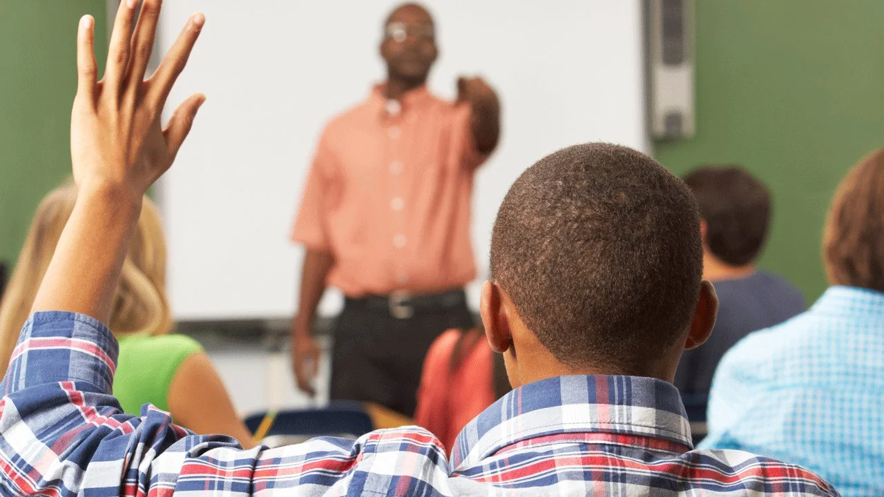 A student raises his hand for a question in class.