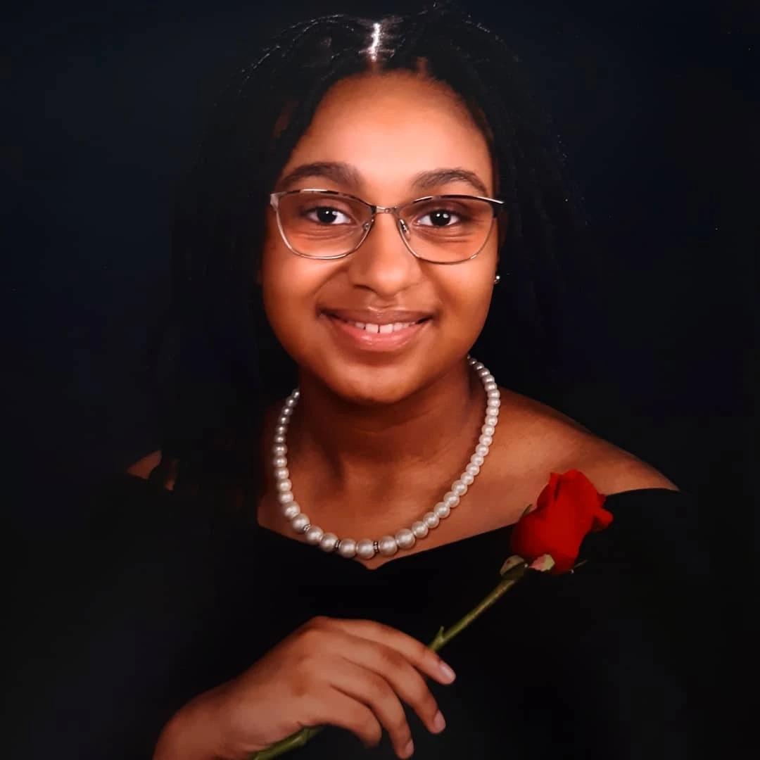 A portrait of Xiani Coubarous-Carter holding a rose.