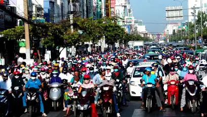 A street scene in Asian showing busy traffic and many scooters.