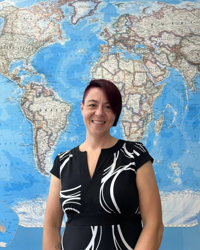 Dr. Amy Widestrom posing in front of global map.