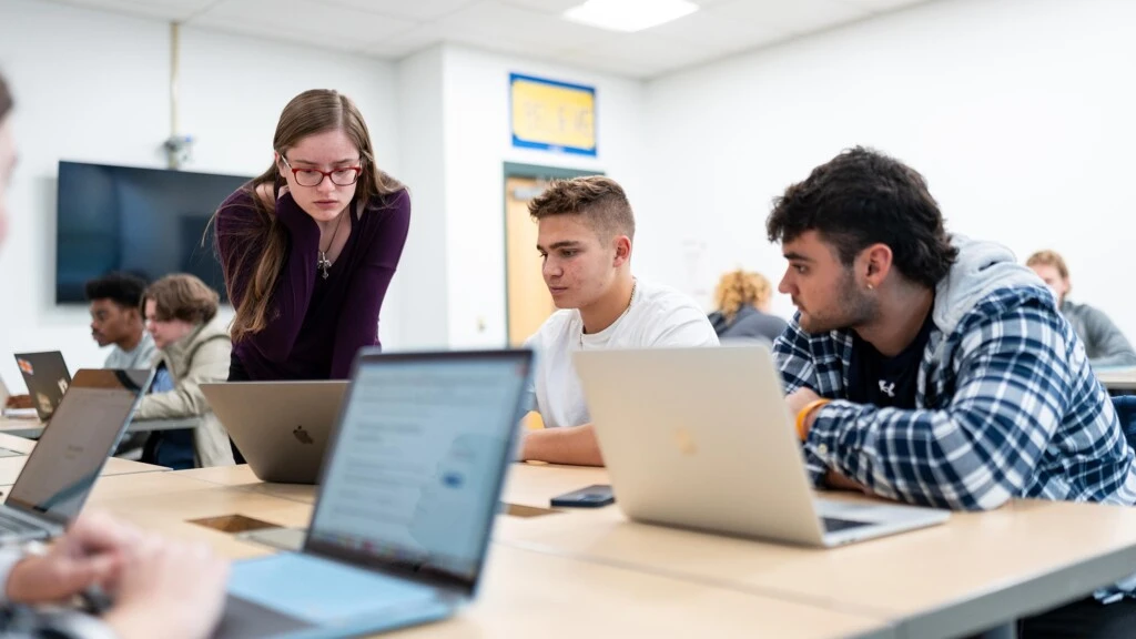 Two undergraduate Arcadia students work an instructor in a classroom.