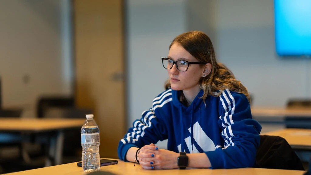 An undergraduate students listens closely to a marketing class lecture.