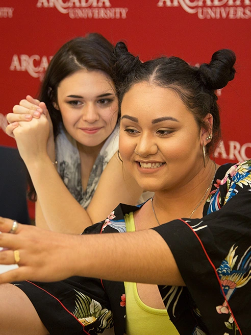 Alexis Diaz ’21, Gender and Sexuality Studies, takes a selfie with a friend in front of an Arcadia backdrop.