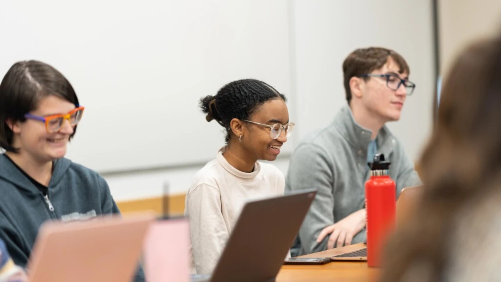 An undergraduate student smiles as when takes notes on her computer during a HAPS class.