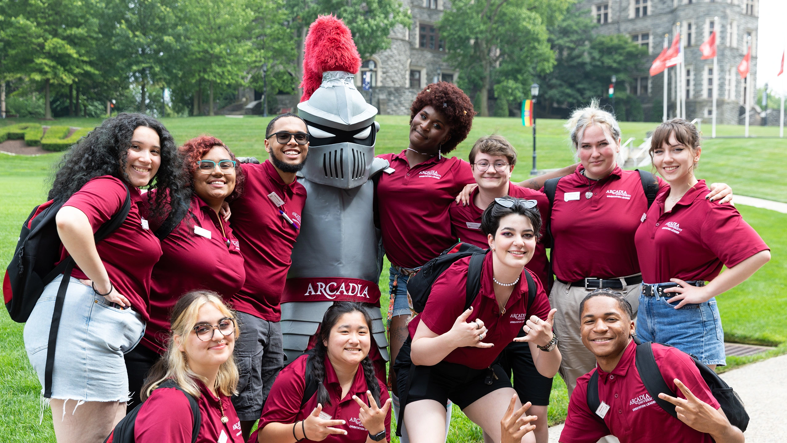 The team from Welcome to Arcadia wearing all-red poses with Archie, Arcadia's mascot.